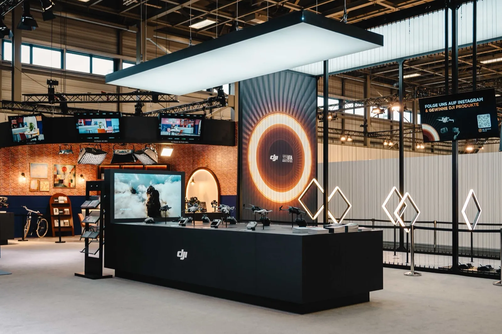 Ein moderner Messestand von DJI mit Drohnen und Bildschirmen in einer großen Halle — DJI auf der IFA Berlin